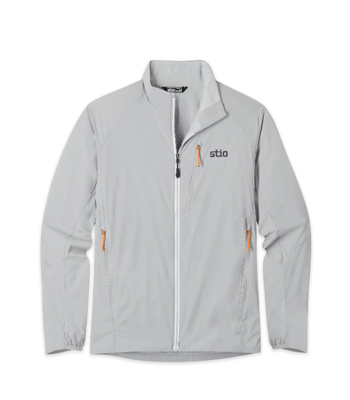 Load image into Gallery viewer, A light gray zip-up jacket with a high collar, featuring a black and gray 'stio' logo on the left chest and bright orange zipper pulls, shown against a plain white background. Ski and Tennis Station

