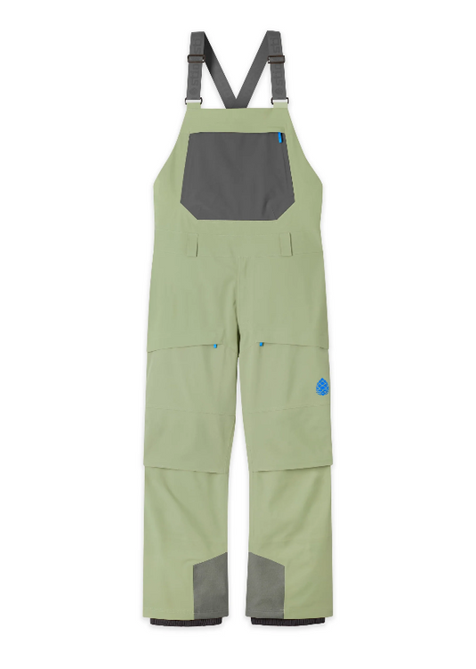 Light sage green bib overalls from Stio with dark gray contrast panels on the chest pocket, suspenders, and lower legs, shown flat against a white background. Ski and Tennis Station.