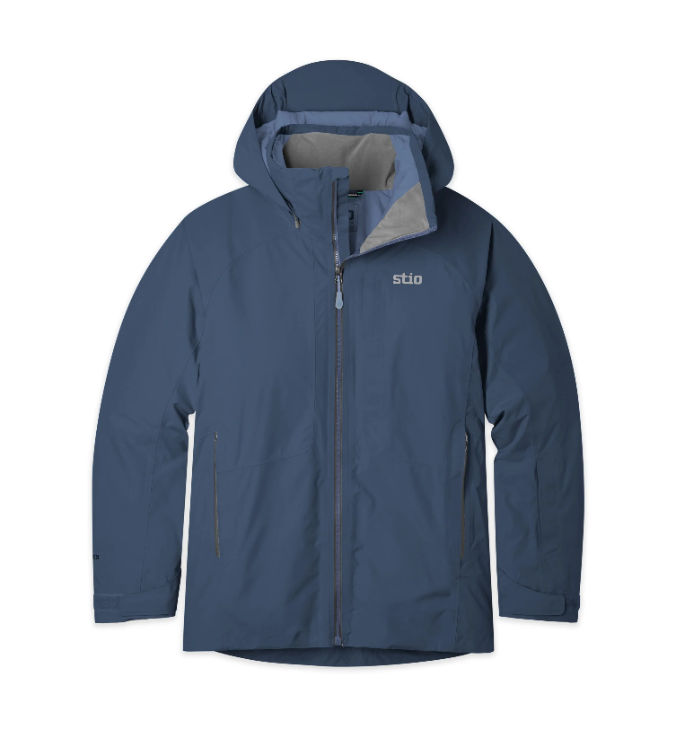 Load image into Gallery viewer, A slate blue hooded outdoor jacket with a full front zipper, zippered hand pockets, and a small white 'stio' logo on the left chest. Ski and Tennis Station
