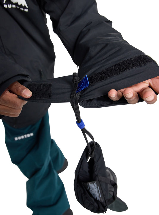 Person wearing a black jacket with a velcro adjustable wrist strap and mitten hanger