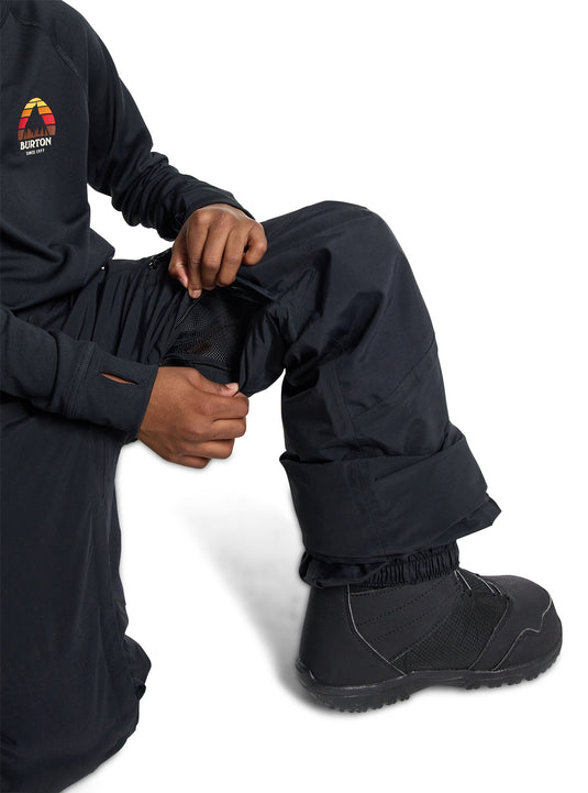 Person wearing black Burton snow pants and boots on a white background