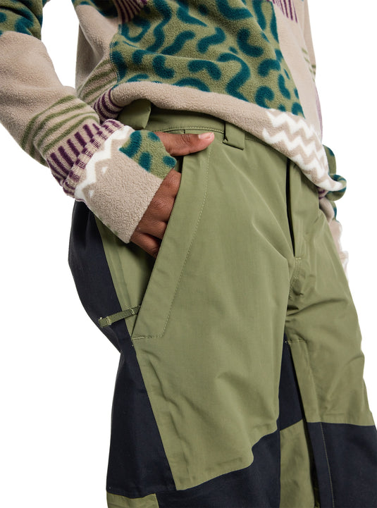 Person wearing a patterned sweater and green snow pants on a white background