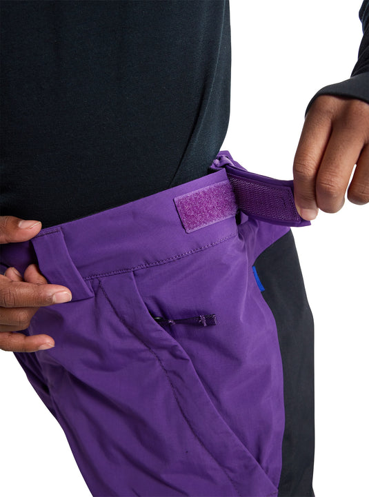 Purple pants with a Burton logo being adjusted by hands on a white background