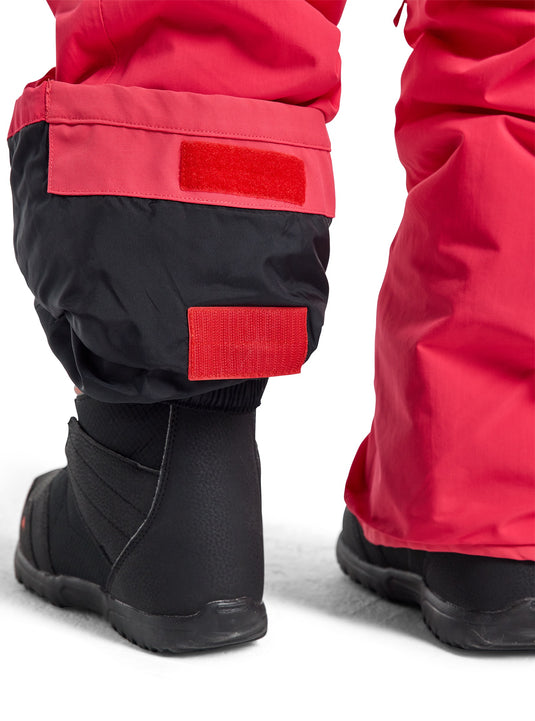 Close-up of red and black winter pants with a black boot on a white background