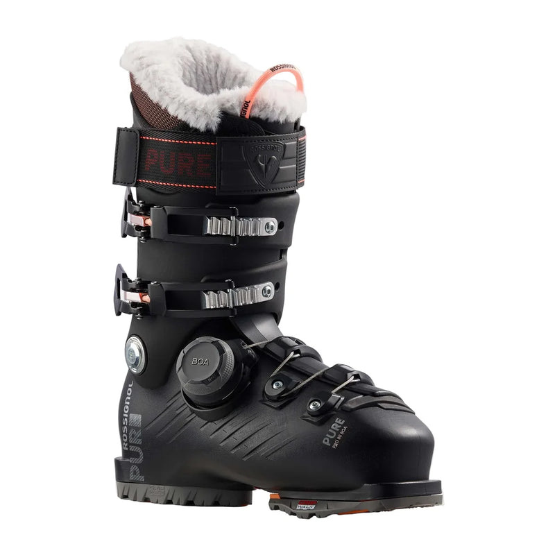 Load image into Gallery viewer, A black ski boot with a white faux-fur collar, orange accents, and a dial closure system, shown on a plain white background.
