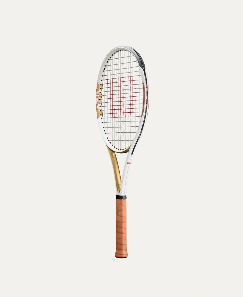 Load image into Gallery viewer, A Wilson Roger Federer HOF Pro tennis racket with a white and gold frame, red string pattern, and a brown grip, shown vertically against a light beige background. Ski and Tennis Station
