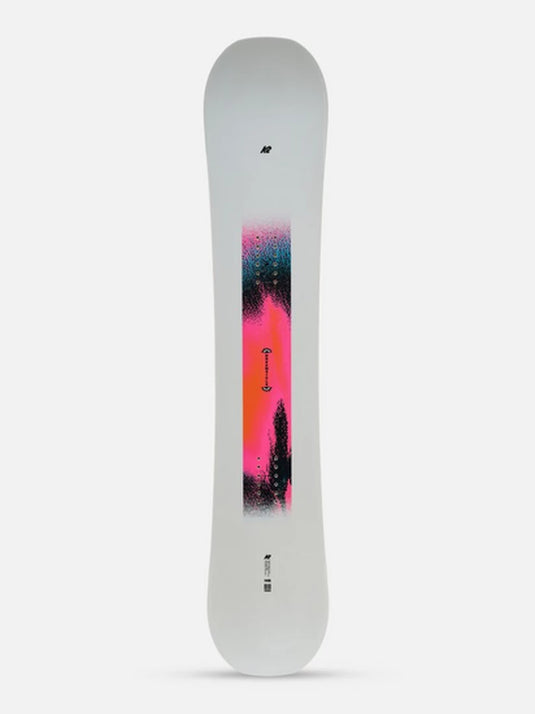 A white K2 snowboard with a vibrant vertical graphic in pink, orange, and blue, shown against a light gray background.