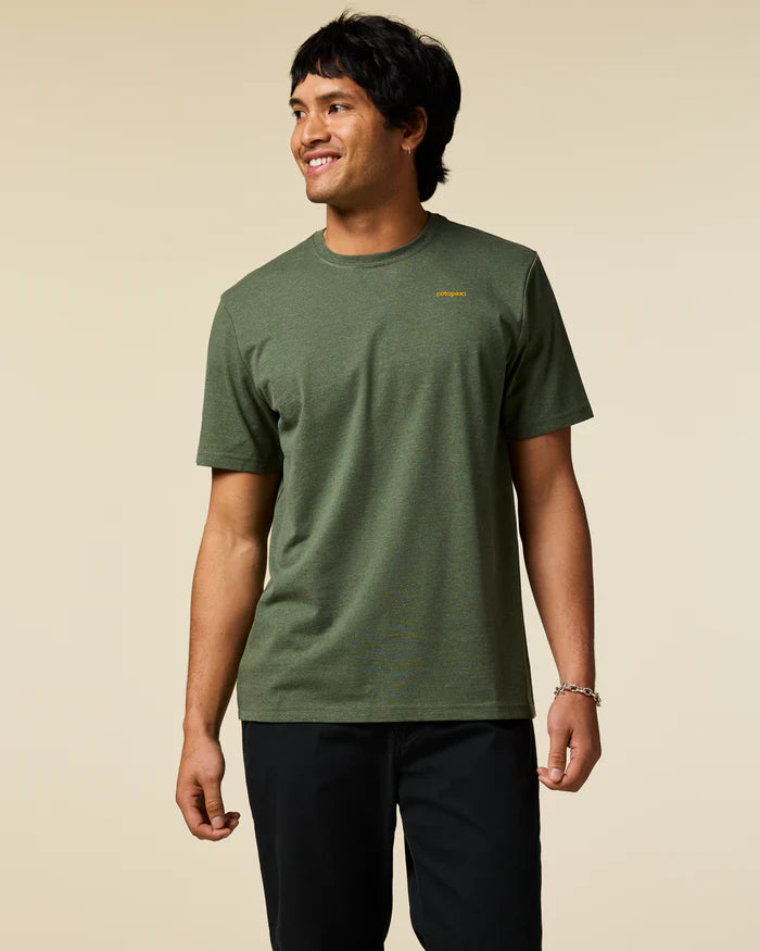 Load image into Gallery viewer, Man wearing a green t-shirt with a Cotopaxi logo on a beige background
