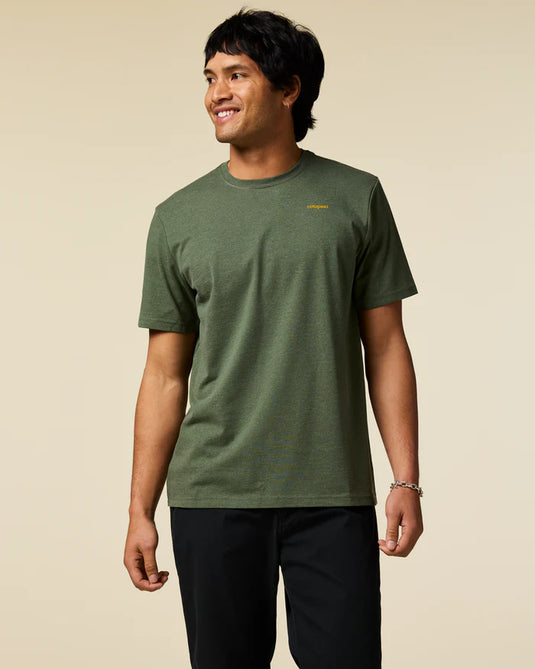 Man wearing a green t-shirt with a Cotopaxi logo on a beige background