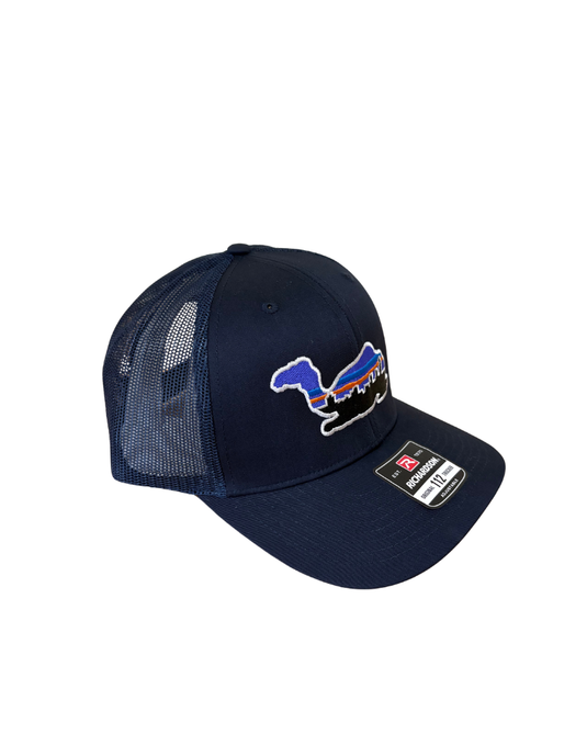 A navy blue trucker hat with a mesh back, featuring a blue, red, and white graphic of a kneeling camel with WS skyline and size/brand sticker on the brim.