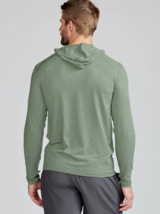 Man wearing a green hoodie and gray pants on a light gray background
